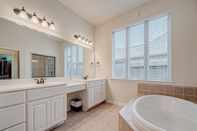 full bath featuring double vanity, a healthy amount of sunlight, a sink, and a bath