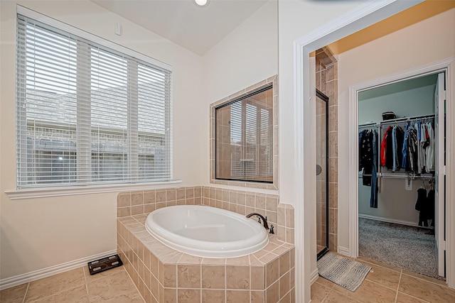 full bath featuring a stall shower, tile patterned flooring, a garden tub, and a walk in closet