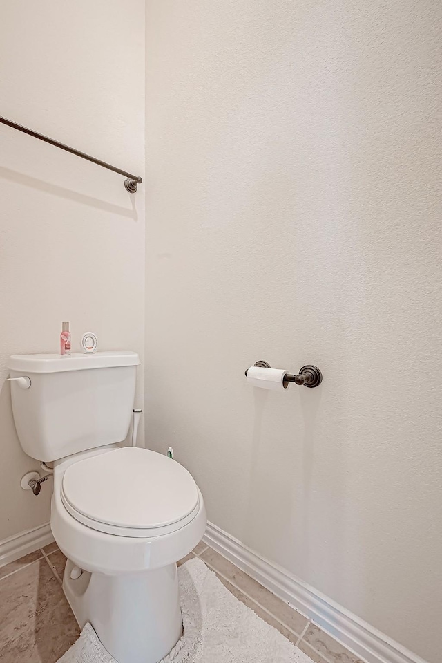 bathroom featuring toilet, baseboards, and tile patterned floors