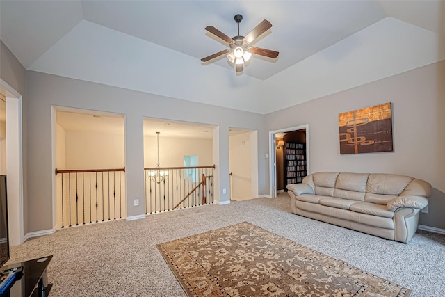 living area with a tray ceiling, vaulted ceiling, and ceiling fan with notable chandelier