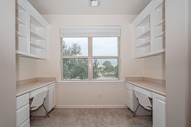 unfurnished office featuring baseboards, visible vents, and built in desk