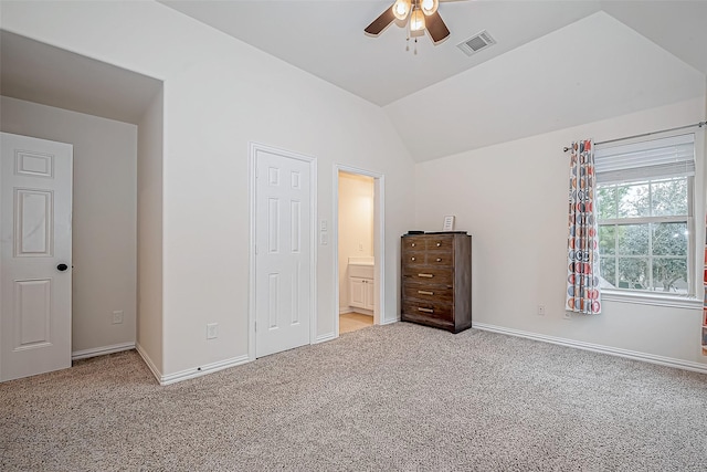 unfurnished bedroom with lofted ceiling, connected bathroom, light carpet, visible vents, and baseboards