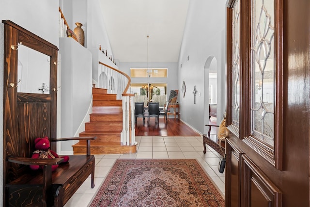 entryway with stairway, arched walkways, a high ceiling, light tile patterned floors, and baseboards