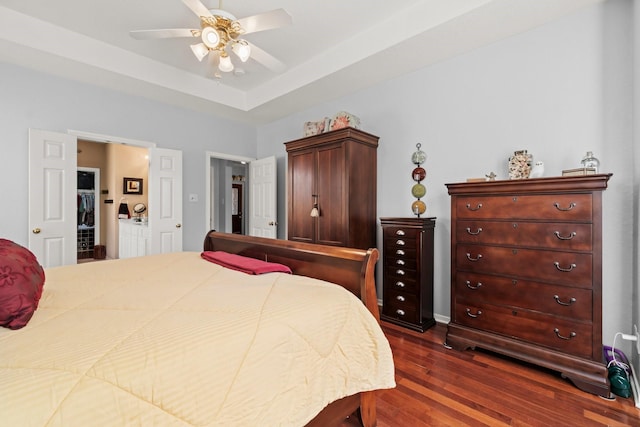 bedroom featuring a raised ceiling, dark wood-style flooring, and ceiling fan