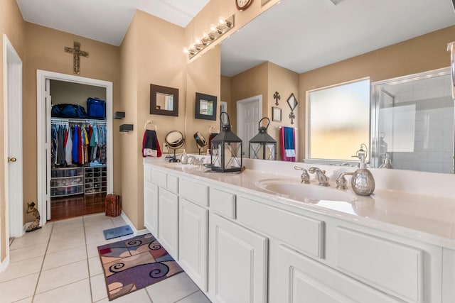 full bath featuring a sink, a stall shower, double vanity, and tile patterned flooring