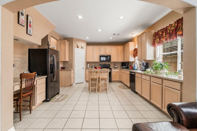 kitchen with light tile patterned flooring, light brown cabinetry, dishwasher, refrigerator with ice dispenser, and range