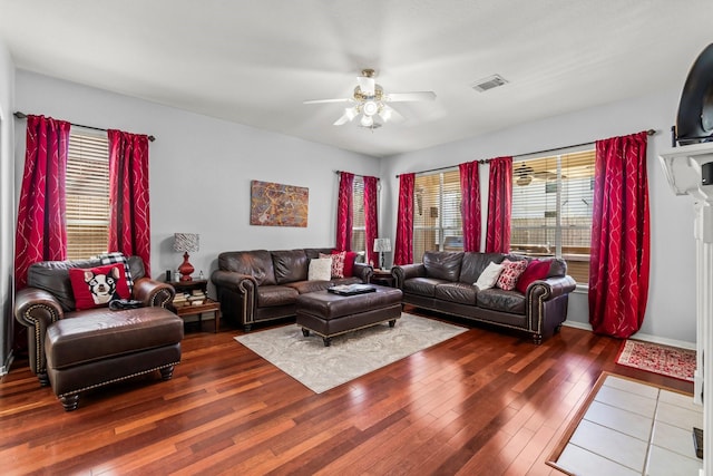 living room with visible vents, baseboards, a ceiling fan, and wood-type flooring