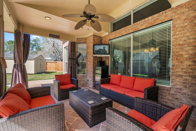 view of patio / terrace with an outdoor living space, ceiling fan, fence, an outbuilding, and a storage unit