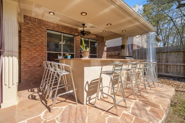 view of patio featuring fence, exterior bar, and ceiling fan