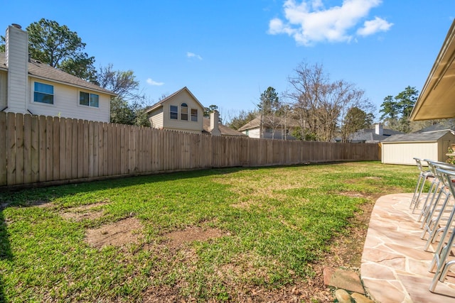 view of yard featuring an outbuilding, a fenced backyard, a shed, and a patio area