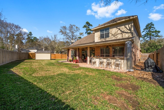 back of property featuring a patio, an outdoor structure, a fenced backyard, and outdoor dry bar