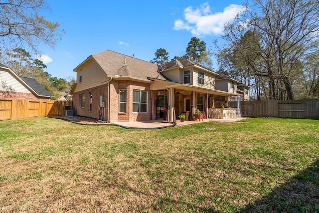 rear view of house with brick siding, a lawn, cooling unit, a fenced backyard, and a patio