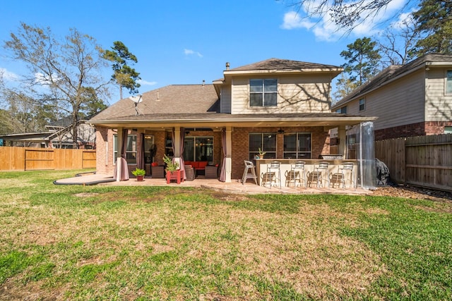 rear view of property with a patio, a yard, a fenced backyard, and brick siding