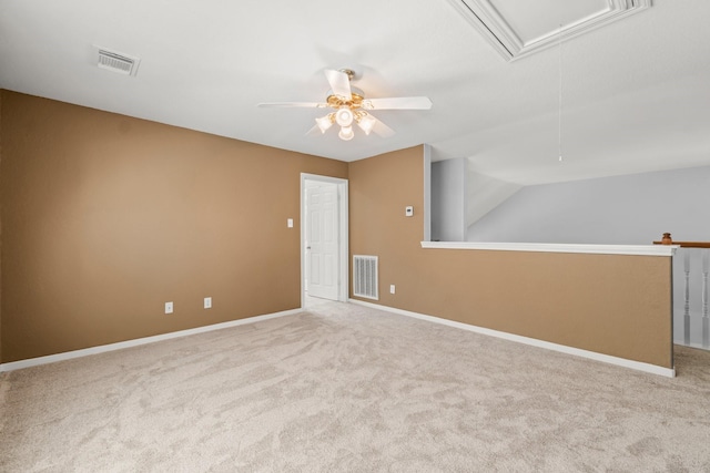 unfurnished room with visible vents, baseboards, attic access, and carpet flooring