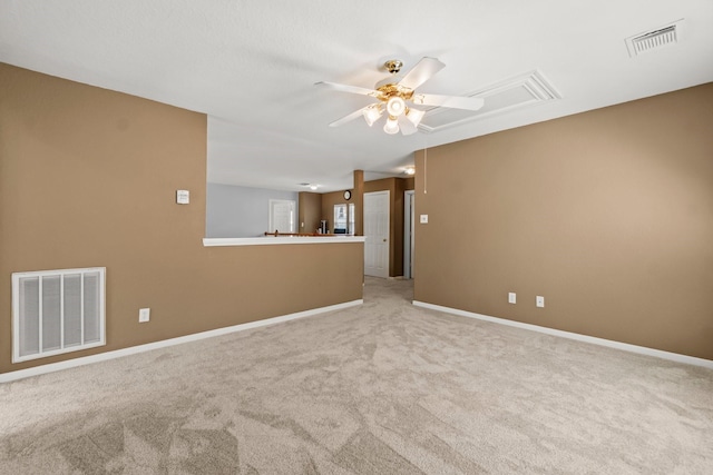 unfurnished room featuring visible vents, light carpet, attic access, and a ceiling fan