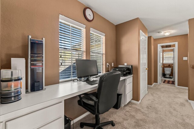 home office featuring baseboards and light carpet