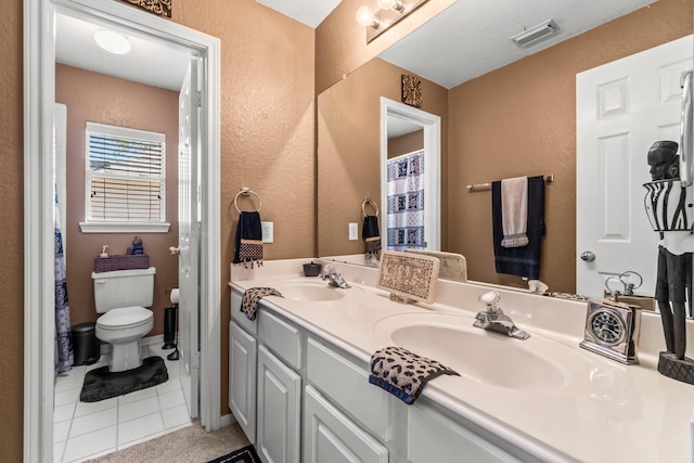 bathroom featuring toilet, a textured wall, visible vents, and a sink