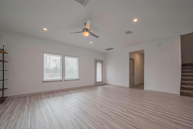 empty room with stairs, light wood-style flooring, and visible vents