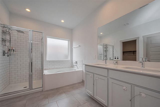 full bath featuring a garden tub, a sink, tile patterned floors, double vanity, and a stall shower