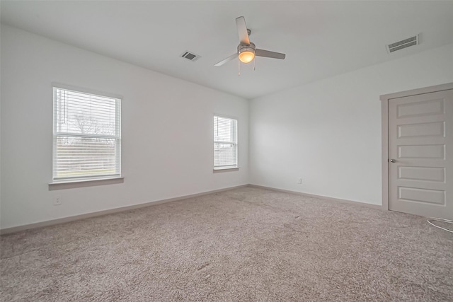 carpeted empty room with a ceiling fan, visible vents, and baseboards