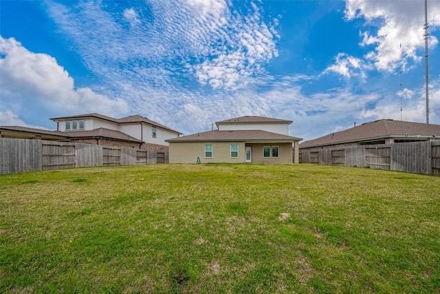 back of property with a fenced backyard and a lawn