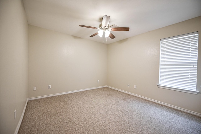 carpeted spare room featuring a ceiling fan and baseboards