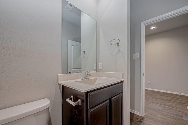 bathroom featuring vanity, wood finished floors, toilet, and baseboards