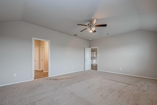 carpeted spare room featuring a ceiling fan, lofted ceiling, visible vents, and baseboards