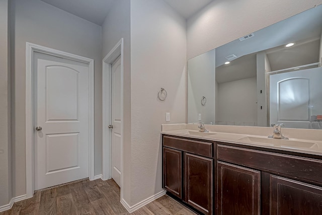 bathroom featuring double vanity, wood finished floors, a sink, and visible vents