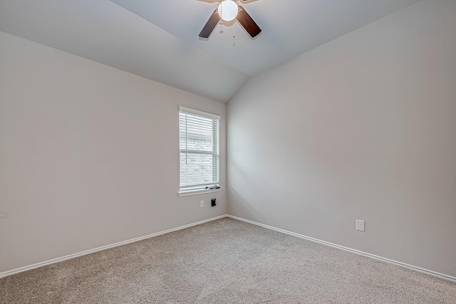 carpeted spare room with vaulted ceiling, a ceiling fan, and baseboards