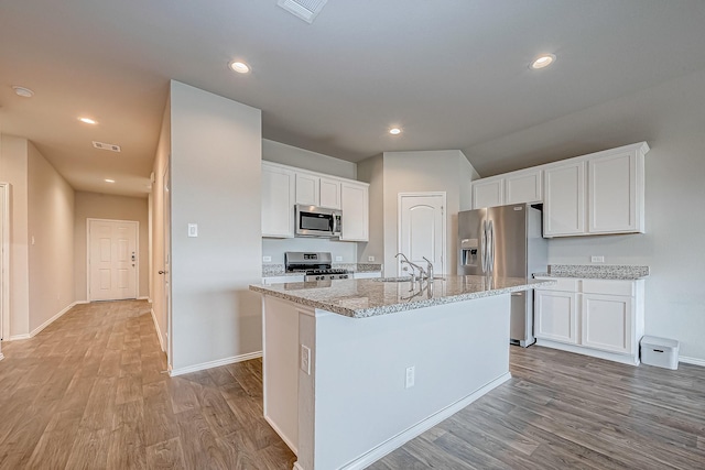 kitchen with visible vents, appliances with stainless steel finishes, white cabinets, a sink, and light wood-type flooring