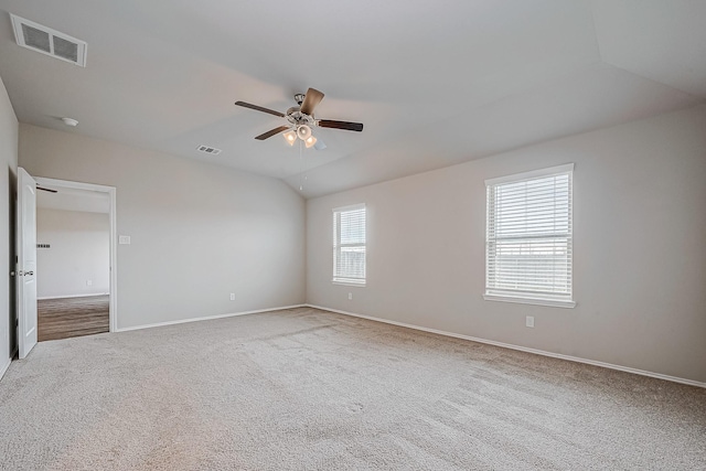 carpeted spare room with lofted ceiling, baseboards, visible vents, and a ceiling fan