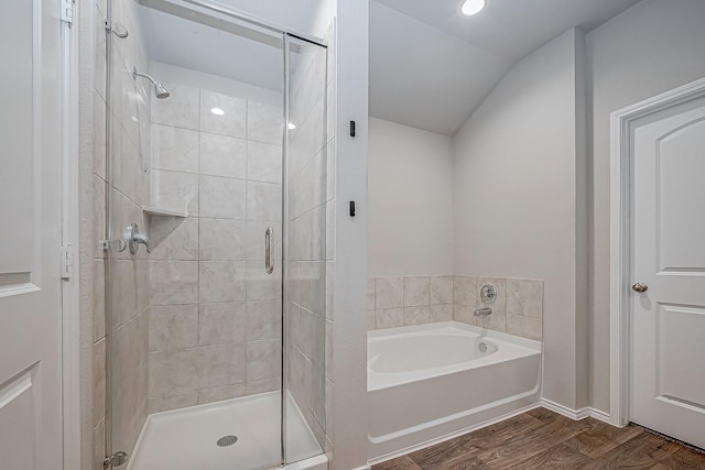 full bathroom featuring a bath, a shower stall, vaulted ceiling, and wood finished floors