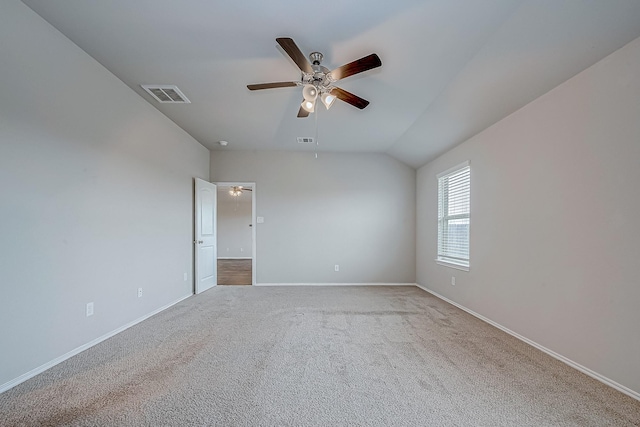 carpeted empty room with a ceiling fan, lofted ceiling, visible vents, and baseboards