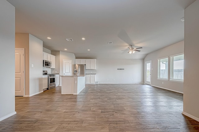 unfurnished living room with ceiling fan, wood finished floors, visible vents, and baseboards