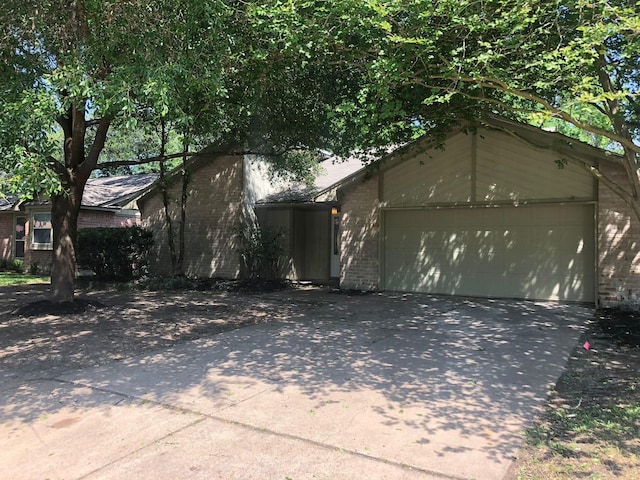 view of front of property featuring a garage, driveway, and brick siding