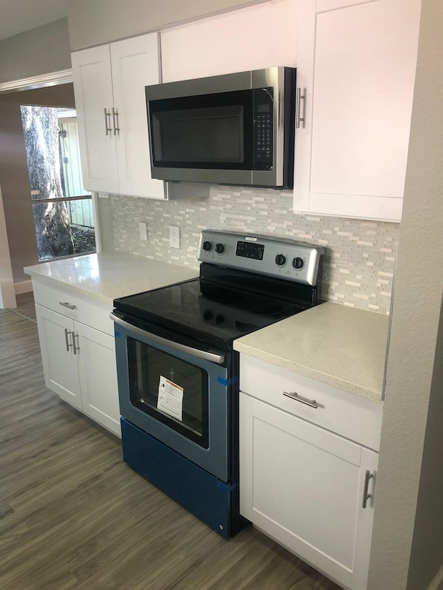 kitchen featuring stainless steel appliances, dark wood-type flooring, white cabinetry, light countertops, and tasteful backsplash