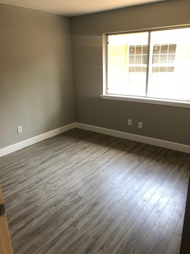 empty room with dark wood-style floors and baseboards