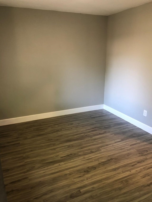 unfurnished room with dark wood finished floors and baseboards