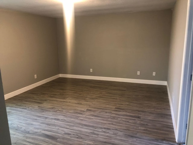 spare room with dark wood-type flooring and baseboards