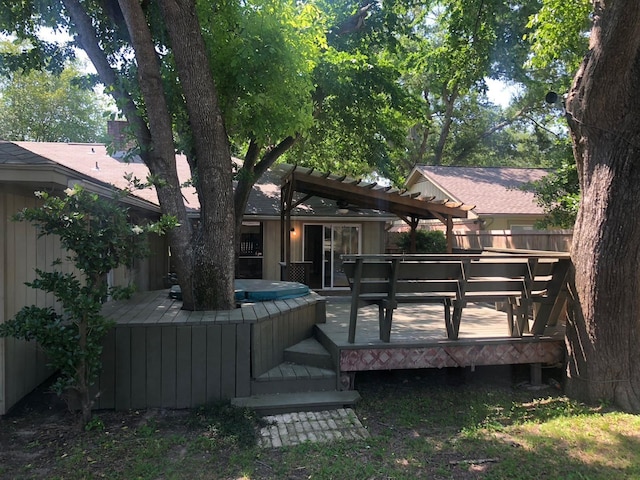 back of house with a covered hot tub, fence, a deck, and a pergola