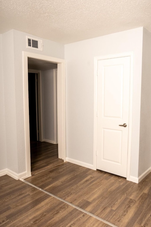 empty room with visible vents, baseboards, a textured ceiling, and wood finished floors