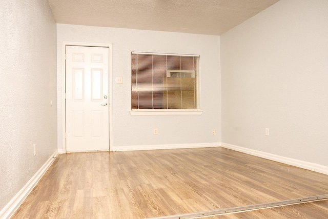 unfurnished room featuring a textured ceiling, light wood-type flooring, and baseboards