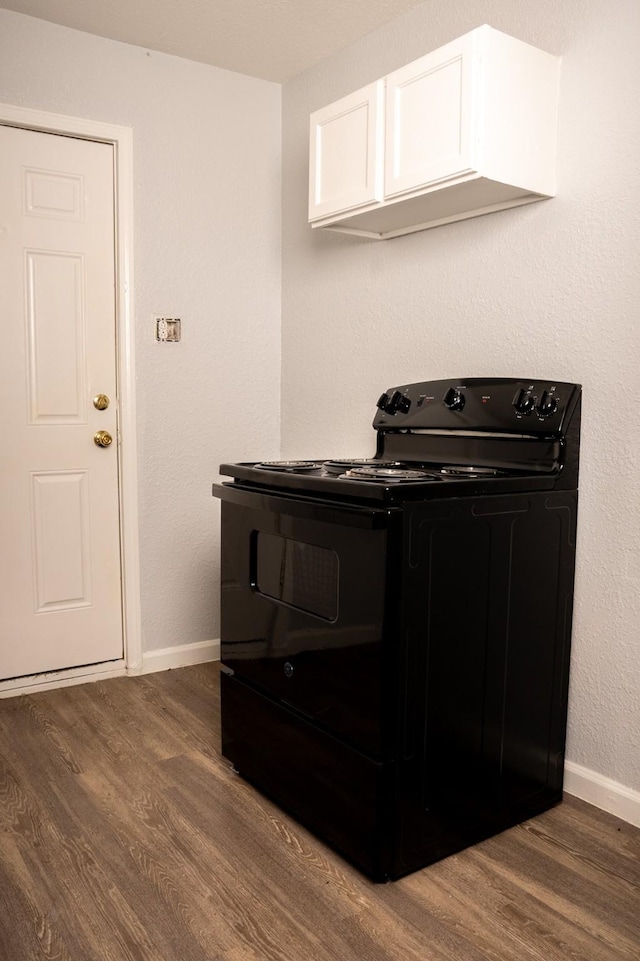 kitchen featuring black electric range, baseboards, dark wood finished floors, and white cabinets