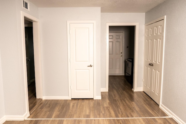 unfurnished bedroom with a closet, visible vents, a textured ceiling, and wood finished floors