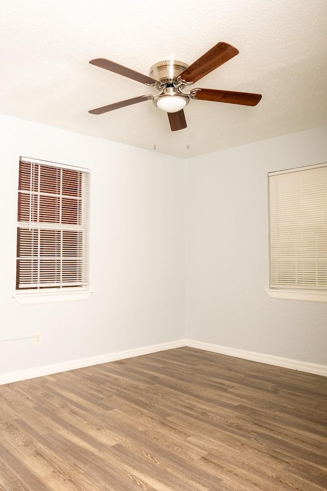 spare room with baseboards and wood finished floors