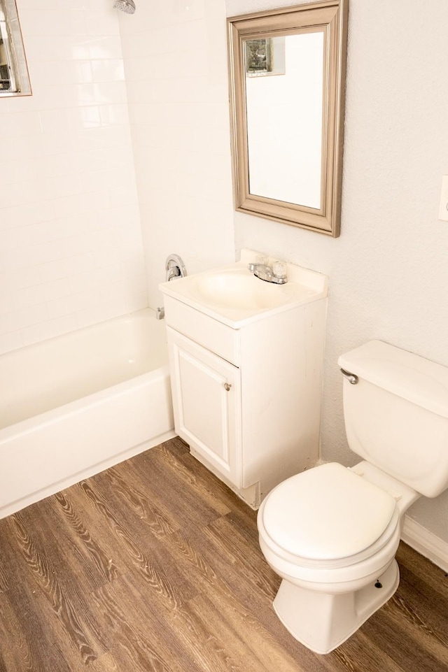 full bath with tub / shower combination, toilet, vanity, and wood finished floors