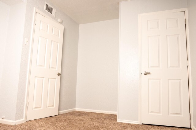 empty room with light colored carpet, visible vents, and baseboards