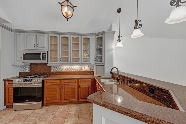 kitchen with a sink, dark stone countertops, backsplash, stainless steel appliances, and glass insert cabinets