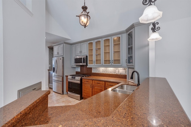 kitchen with gray cabinets, a sink, stainless steel appliances, glass insert cabinets, and dark countertops